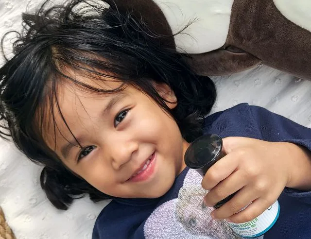 Anak kecil memegang botol minyak rambut bayi Aeva